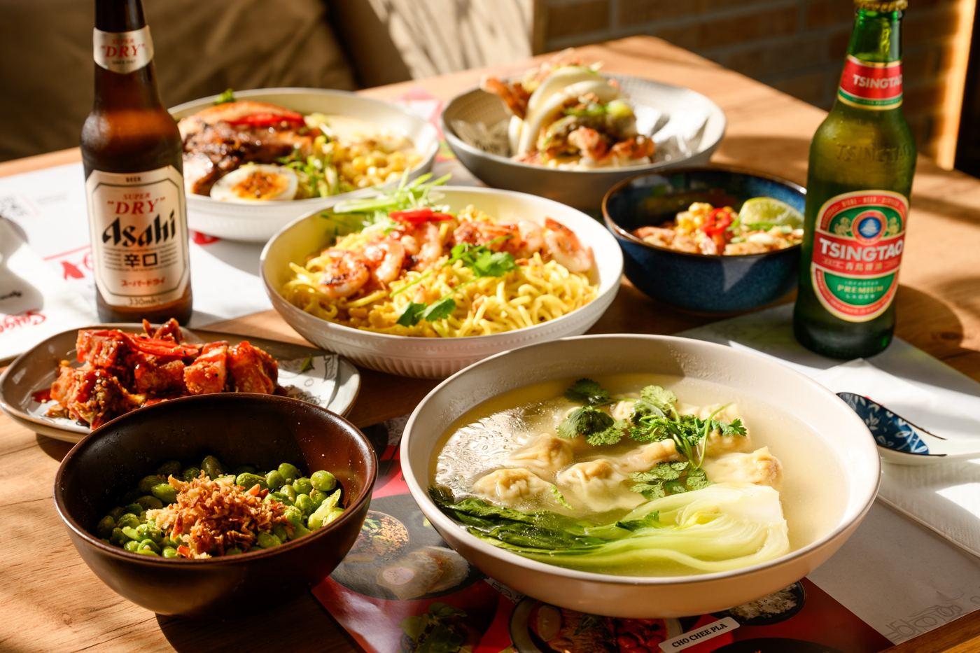 A full Saigon table — bao, wings, noodles and cold beer, shot from above